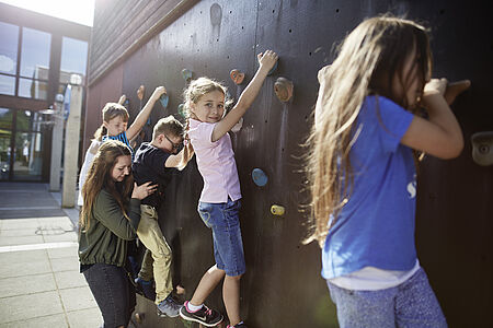 Kinder klettern an einer Kletterwand